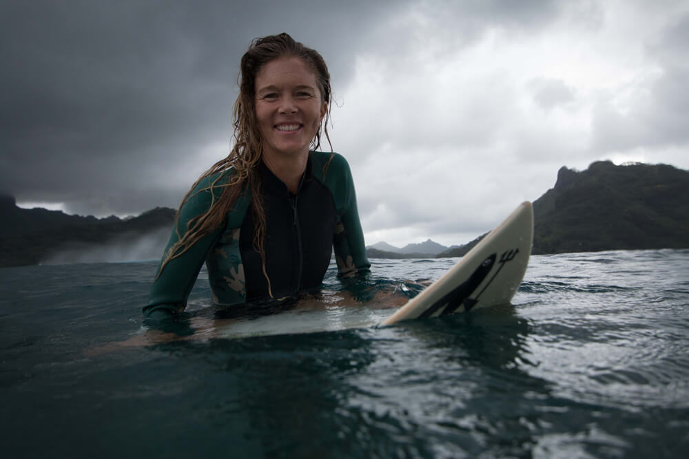Liz Clark sitting on surf board in the water